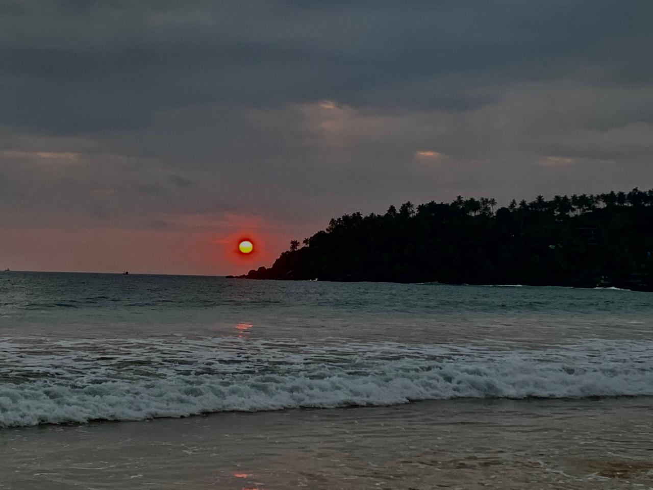 Sunset over the Indian Ocean on Sri Lanka's south coast, palm-fringed headland